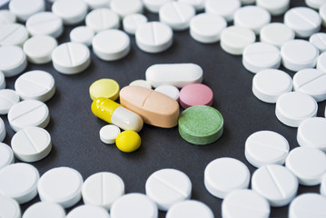 Colourful pills surrounded by white round pills
