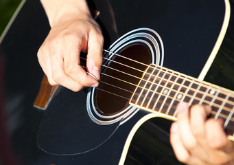 Obraz na płótnie Canvas playing a black accoustic guitar