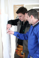 Obraz premium Ouvriers devant plan de chantier