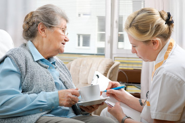 Senior woman is visited  by her doctor or caregiver