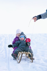 Fototapeta na wymiar Winter joy - Small children in sledge during snow pulled by a ma