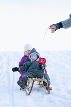Winter joy - Small children in sledge during snow pulled by a ma