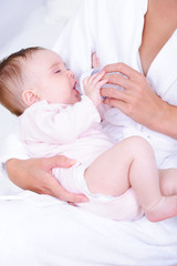 Obraz na płótnie Canvas Baby drinking milk from bottle by nurse