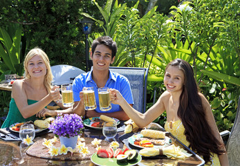 three friends having a barbecue lunch in their tropical garden