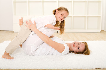 Little girl and woman playing indoors on the floor