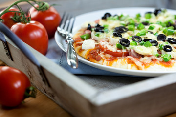 Pizza with vegetables and ham served on rustic wooden tray