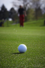 Golf ball close-up with golfer man at the background