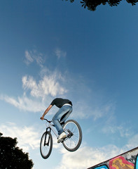 Biker jumping high on a ramp against blue sky.