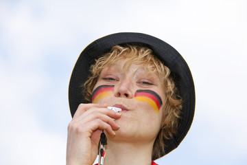 weiblicher Deutschlandfan bläst in Trillerpfeife