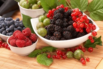 Berries in plates, on a table, among green leaves