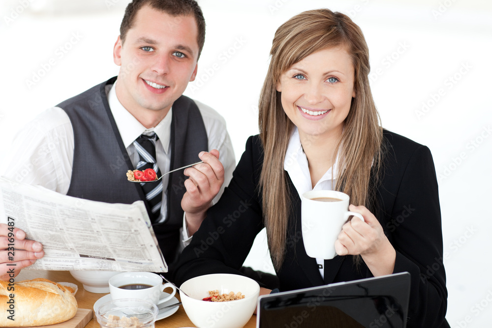 Canvas Prints Young couple of business people reading a newspaper while having