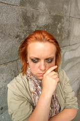 Young worried woman against old stone wall