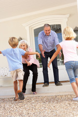 Grandparents Welcoming Grandchildren On Visit To Home