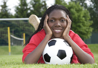 Naklejka premium Junge Afrikanerin mit Fussball vor dem Tor liegend
