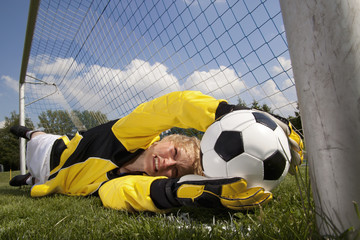 junge blonde Frau im Fussballtor fängt ball