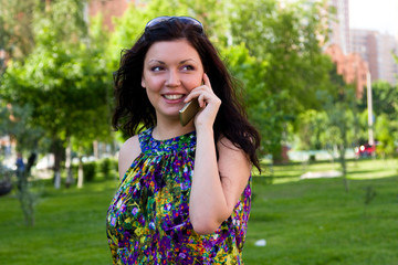 Woman is talking mobile phone outdoors.