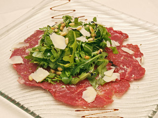 beef carpaccio with salad on a plate, white background