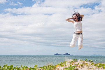 Attractive woman jumping of joy on tropical beach