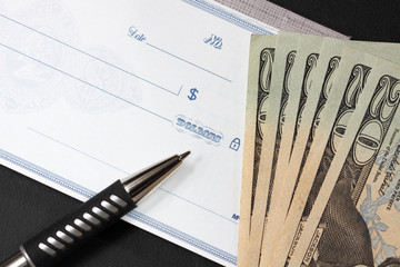 blank check with twenty dollar bills at its side