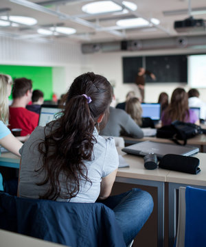 Young Pretty Female College Student Sitting In A Classroom Full