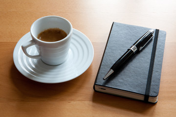 Espresso neben Stapel von Notizbüchern, Tagebüchern mit Stift