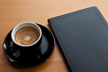 schwarze Tasse mit Espresso und Tagebuch