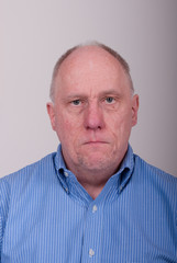 Obraz premium Older Balding Man in Blue Shirt Looking Unhappy