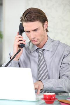 Homme d'affaires téléphonant devant ordinateur portable