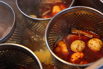 Fish balls cooking in chili sauce in a market