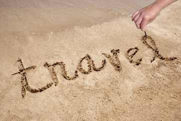 Travel handwritten in sand on a beach