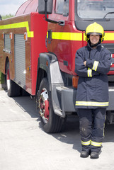 Portrait of female firefighter standing in front of fire engine