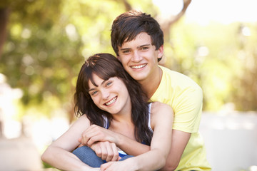 Fototapeta premium Portrait Of Romantic Teenage Couple Sitting In Park