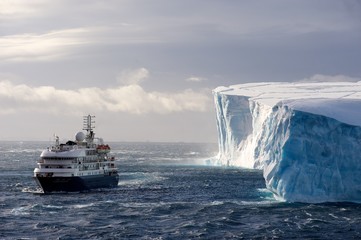 The cruise ship Corinthian II in front of a huge Iceberg - obrazy, fototapety, plakaty