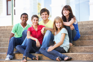 Obraz premium Group Of Teenage Friends Sitting On College Steps Outside