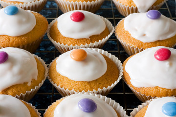 Iced buns on a tray with coloured sweet tops