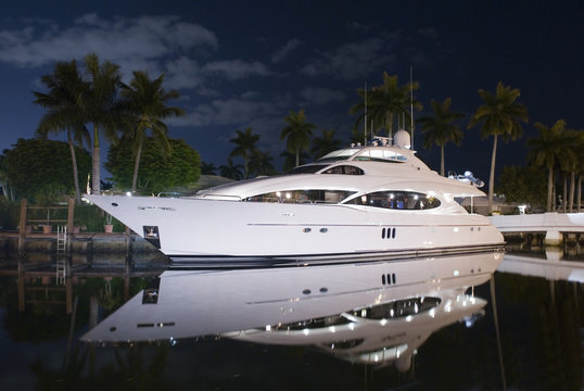 Fototapeta night shot of luxury yacht docked by the house in canal palm trees and moon light