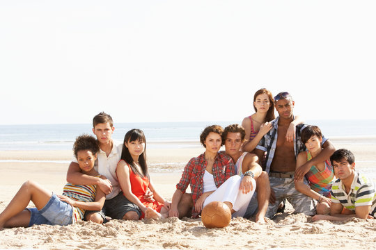 Group Of Friends Sitting On Beach Together