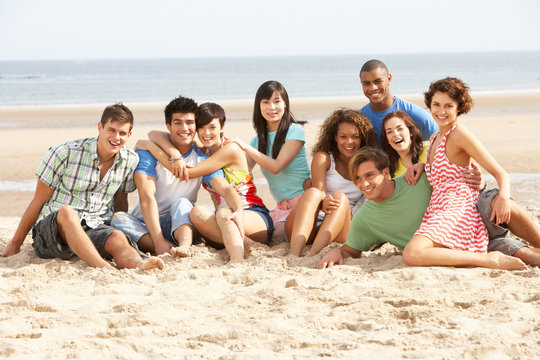 Group Of Friends Sitting On Beach Together