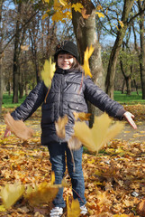 pretty child pick up of leaves in autumn park