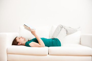 junge frau liest auf sofa buch