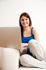 Naklejka premium junge frau entspannt sich zu hause auf sofa mit laptop