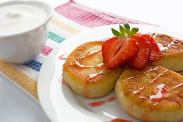 Cheese pancakes with sour cream, syrup and strawberry