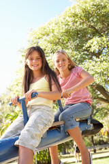 Naklejka na ściany i meble Two Girls Riding On See Saw In Playground