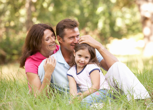 Family Sitting In Long Grass In Park