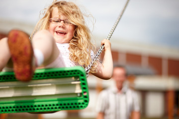 Mädchen schaukelt auf Spielplatz