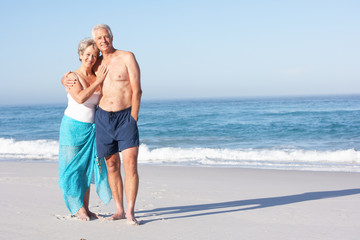 Senior Couple On Holiday Walking Along Sandy Beach