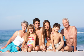 Fototapeta na wymiar Three Generation Family On Holiday Walking Along Beach