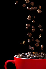 Coffee beans falling in red cup