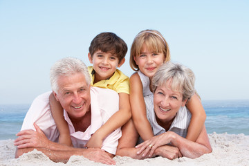 Grandparents And Grandchildren Relaxing On Beach Holiday