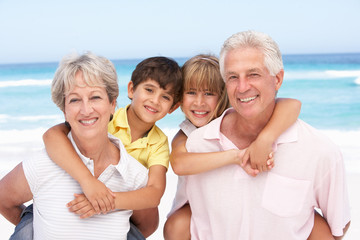 Grandparents And Grandchildren Relaxing On Beach Holiday